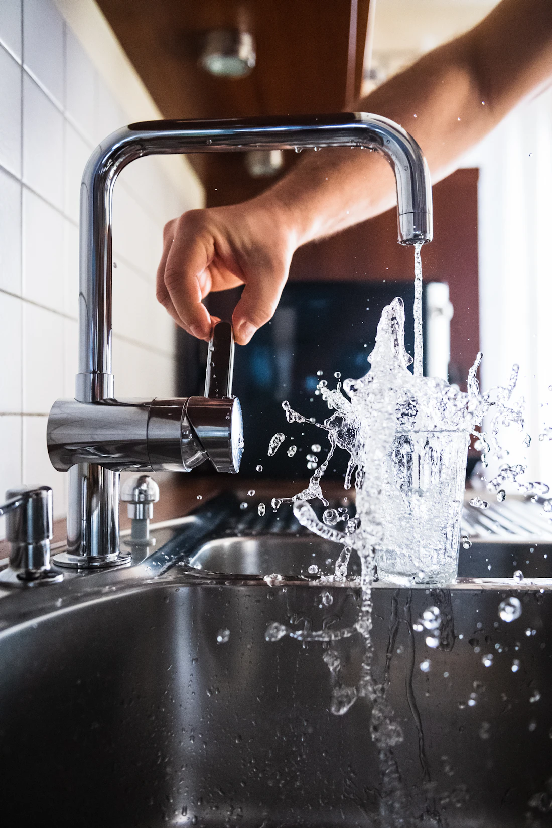Water running from a modern kitchen faucet into a glass