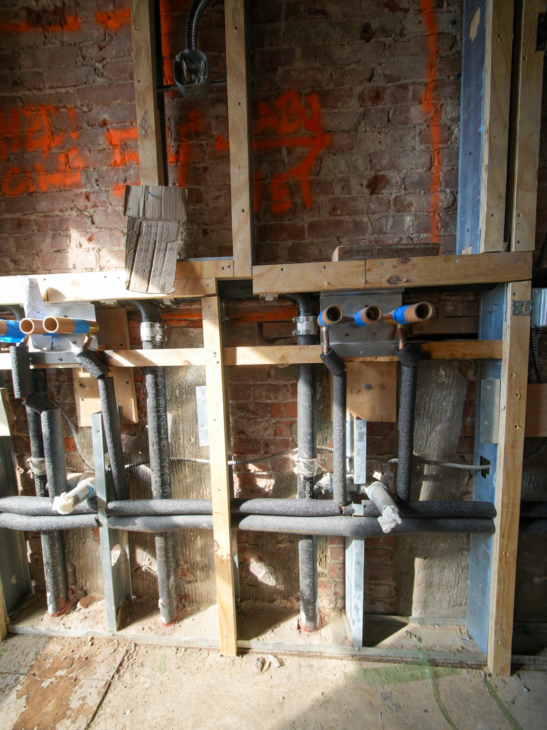 New copper and plastic plumbing lines in an open wall during a remodel