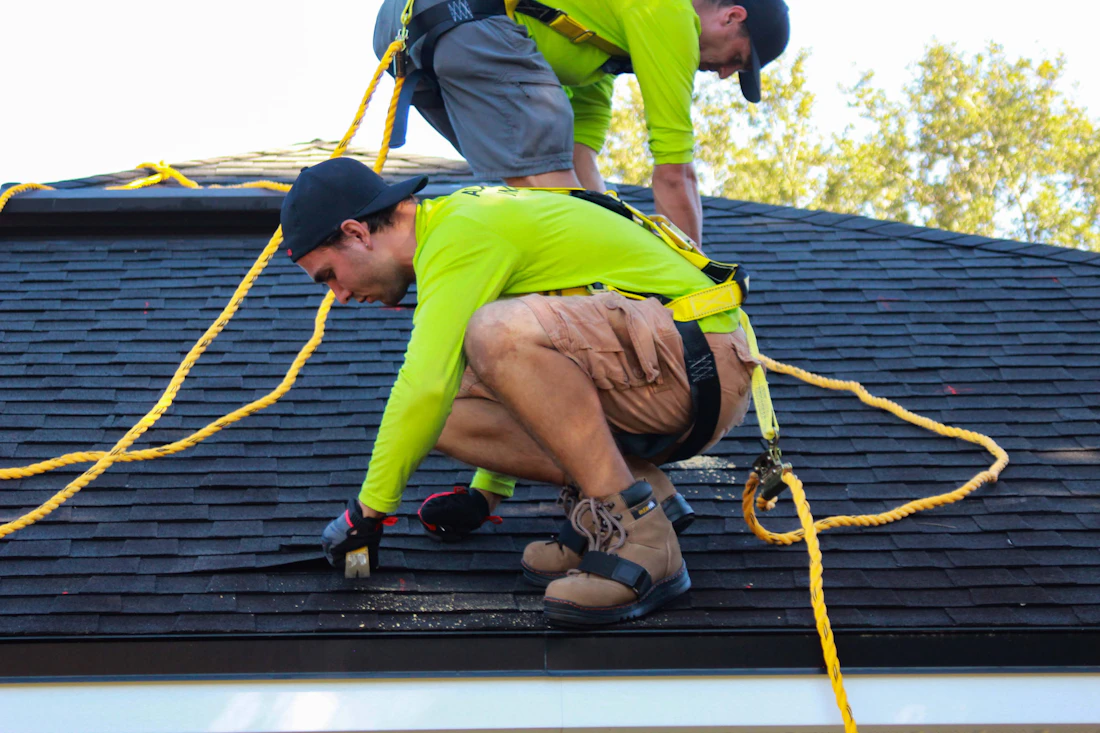 Two roofers working together on the roof of a house